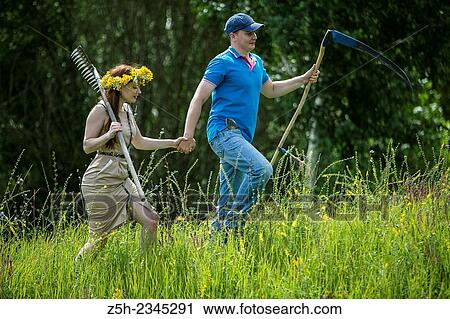 Stock Image - Young couple with an agricultural tool in the field.. Fotosearch