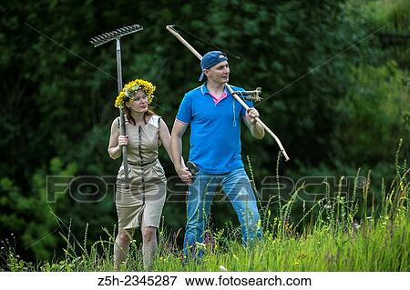 Stock Photo - Young couple with an agricultural tool in the field.. Fotosearch