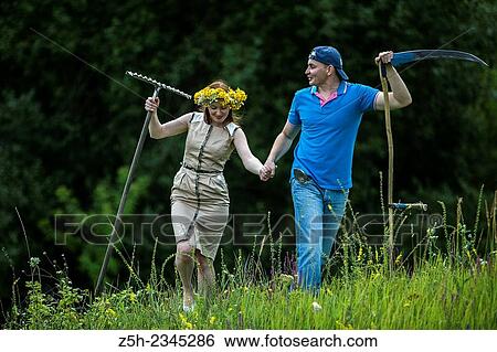 Stock Photograph - Young couple with an agricultural tool in the field.. Fotosearch