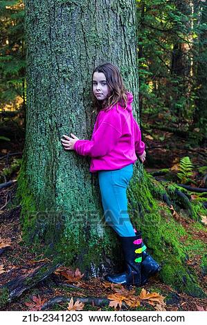Young girl in a temperate rain forest hugging a fir tree. View Large Photo Image Stock Image - Young girl in a temperate rain forest hugging a fir tree.. Fotosearch