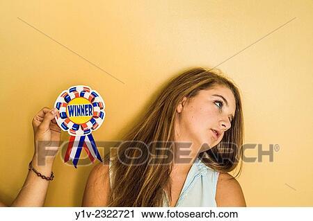 Stock Image - Young woman holding an award next to her teen sister.. Fotosearch