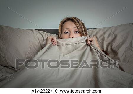 Stock Image - Young woman lying on her bed.. Fotosearch