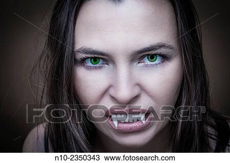 Stock Image - Young woman wearing fake vampire teeth.. Fotosearch
