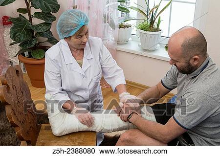 Stock Image - A man with a broken leg. Paramedic and patient.. Fotosearch