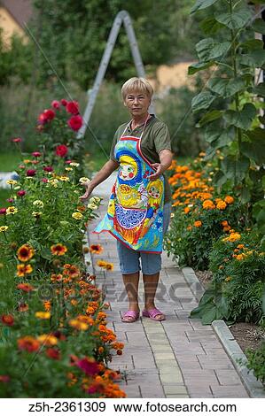 Stock Photo - A woman in a summer blossoming garden.. Fotosearch