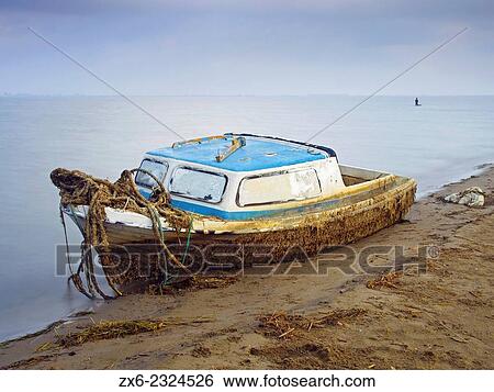 Stock Photograph - "Abandoned small fishing boat after a storm at Alfacs bay. Trabucador Isthmus. Ebro River Delta Natural Park, Tarragona province, Catalonia, Spain. ". Fotosearch