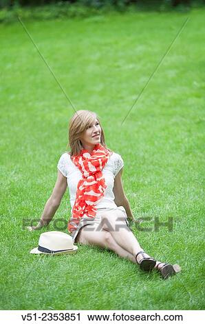 Stock Image - Blonde beautiful woman sitting in the park in Spring. Fotosearch