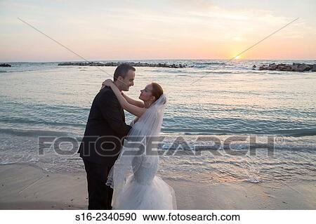 Bride and groom about to kiss on the beach on sunrise/ sunset background. View Large Photo Image Stock Image - Bride and groom about to kiss on the beach on sunrise/ sunset background.. Fotosearch