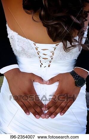 "bride and groom on wedding day, and groom embracing bride with hands in shape of heart" View Large Photo Image Stock Photo - "bride and groom on wedding day, and groom embracing bride with hands in shape of heart". Fotosearch