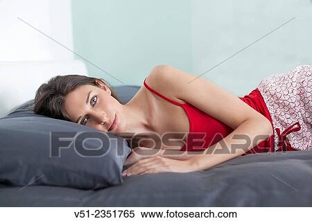 Brunette woman lying in bed looking at camera View Large Photo Image Stock Photography - Brunette woman lying in bed looking at camera. Fotosearch