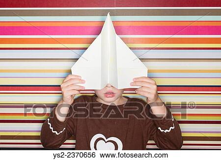 Child holding paper airplane in front of face. View Large Photo Image Stock Photograph - Child holding paper airplane in front of face.. Fotosearch