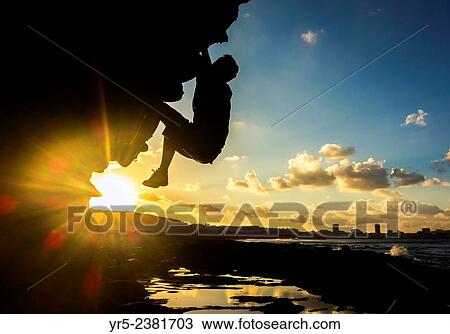 Stock Image - "Climber on volcanic coastal boulder at sunrise at El Confital, Las Palmas, Gran Canaria, Canary Islands, Spain. ". Fotosearch