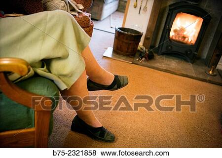 "Closeup of an elderly lady legs resting sitting in an armchair near a wood stove on a cottage in Yorkshire, England, UK" View Large Photo Image Stock Photo - "Closeup of an elderly lady legs resting sitting in an armchair near a wood stove on a cottage in Yorkshire, England, UK". Fotosearch