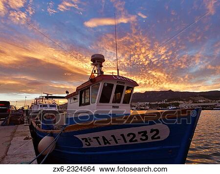 Picture - "Colorful sunset with cirrocumulus clouds over Sant Carles de la Rapita fishing port. Ebro River Delta Natural Park, Tarragona province, Catalonia, Spain. ". Fotosearch