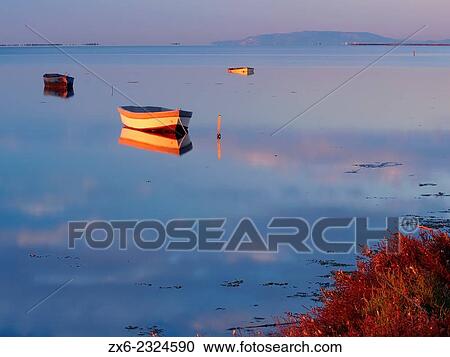 Stock Image - "First sunrays over fishing boats at Alfacs Bay. Ebro River Delta Natural Park, Tarragona province, Catalonia, Spain. ". Fotosearch