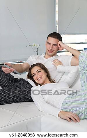Stock Photo - Happy young couple at sofa enjoying TV. Fotosearch