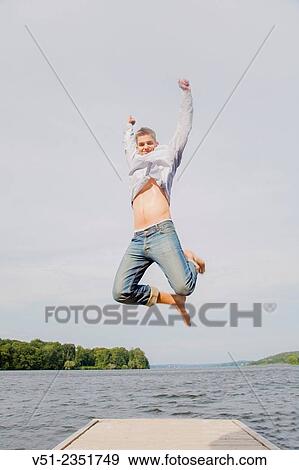 Happy young man jumping in a pier by the sea View Large Photo Image Stock Photo - Happy young man jumping in a pier by the sea. Fotosearch
