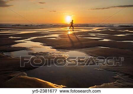 Stock Photo - "Jogger at sunrise on Seaton Carew beach, north east Enngland. United Kingdom. ". Fotosearch