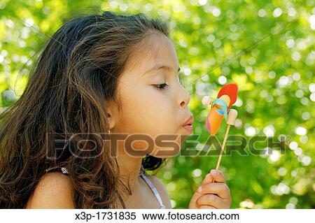 Latin little girl blowing a windmill View Large Photo Image Stock Photography - Latin little girl blowing a windmill. Fotosearch