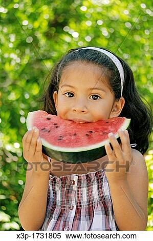 Stock Photography - Latin little girl eating watermelon. Fotosearch