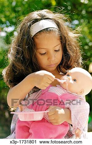 Latin little girl feeding a doll View Large Photo Image Stock Image - Latin little girl feeding a doll. Fotosearch