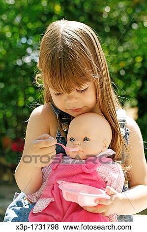 Little girl feeding a doll View Large Photo Image Stock Photo - Little girl feeding a doll. Fotosearch