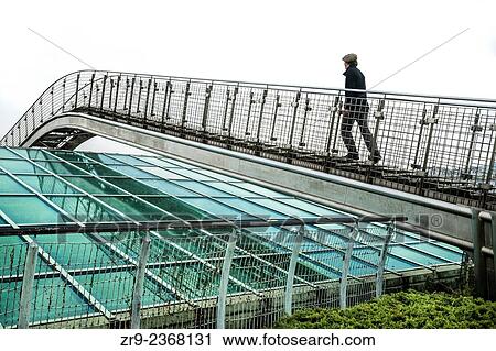 "Man ascends a metal bridge over a glass roof at the Warsaw University Library garden, designed by Irena Bajerska and opened in 2002, Politechnika Warszawska, Warsaw, Poland, Europe. " View Large Photo Image Stock Image - "Man ascends a metal bridge over a glass roof at the Warsaw University Library garden, designed by Irena Bajerska and opened in 2002, Politechnika Warszawska, Warsaw, Poland, Europe. ". Fotosearch