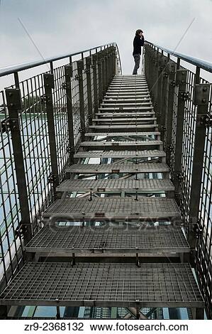 "Man ascends a metal bridge over a glass roof at the Warsaw University Library garden, designed by Irena Bajerska and opened in 2002, Politechnika Warszawska, Warsaw, Poland, Europe. " View Large Photo Image Stock Image - "Man ascends a metal bridge over a glass roof at the Warsaw University Library garden, designed by Irena Bajerska and opened in 2002, Politechnika Warszawska, Warsaw, Poland, Europe. ". Fotosearch