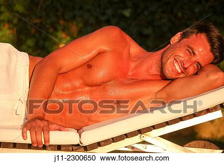 Man lying down on sunlounger View Large Photo Image Stock Image - Man lying down on sunlounger. Fotosearch