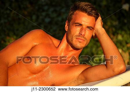 Stock Image - Man lying down on sunlounger. Fotosearch