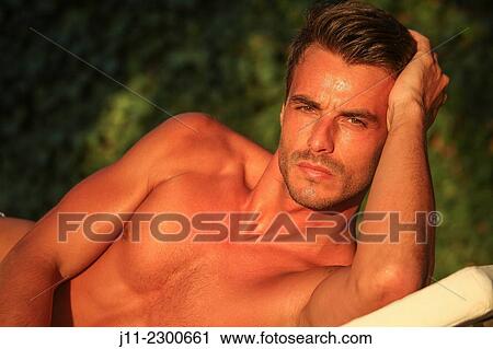 Stock Image - Man lying down on sunlounger. Fotosearch