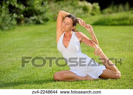 Picture - "Middle aged woman doing yoga in a park in summer, Germany. ". Fotosearch