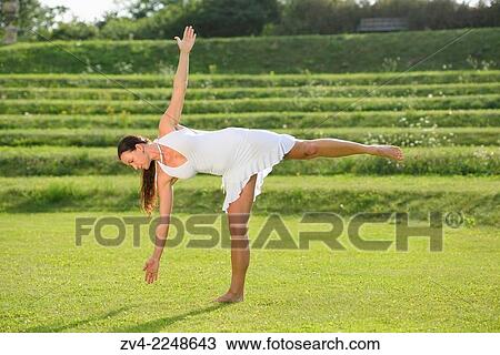 Stock Image - "Middle aged woman doing yoga in a park in summer, Germany. ". Fotosearch