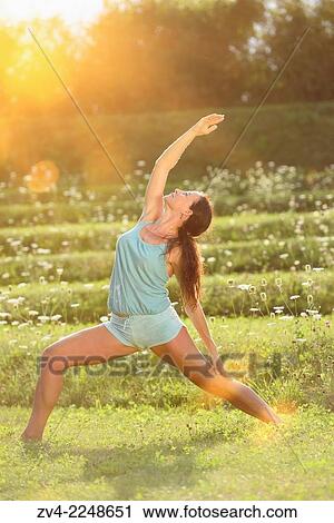Stock Image - "Middle aged woman doing yoga in a park in summer, Germany. ". Fotosearch