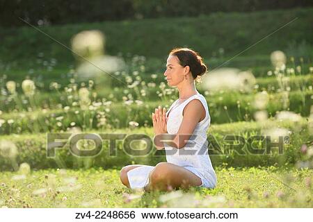 Stock Photograph - "Middle aged woman doing yoga in a park in summer, Germany. ". Fotosearch