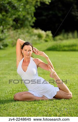 Stock Photography - "Middle aged woman doing yoga in a park in summer, Germany. ". Fotosearch