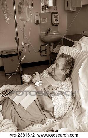 Stock Image - Ninety year old lady in NHS hospital recovering following general anaesthetc. Arrow on arm indicates to surgeon procedure is on left side of body.. Fotosearch