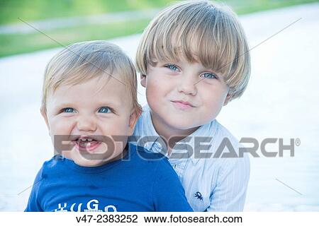 Stock Image - Portrait a baby and his older brother smiling at camera. Fotosearch