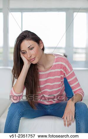 Portrait of a pensive pretty woman sitting on the sofa View Large Photo Image Stock Photo - Portrait of a pensive pretty woman sitting on the sofa. Fotosearch