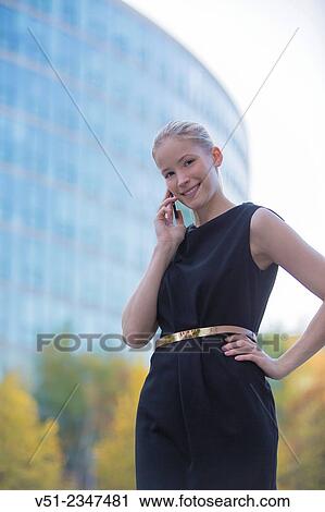 Portrait of a woman with mobile phone in downtown smiling at camera View Large Photo Image Stock Image - Portrait of a woman with mobile phone in downtown smiling at camera. Fotosearch