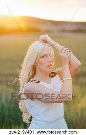 Stock Image - Portrait of a young woman in cornfield at sunset.. Fotosearch
