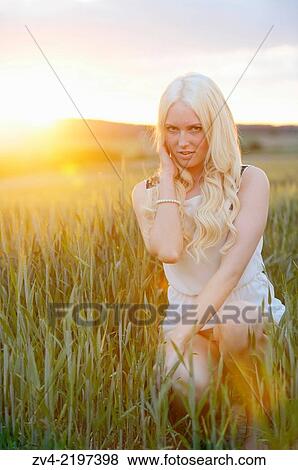 Stock Photo - Portrait of a young woman in cornfield at sunset.. Fotosearch