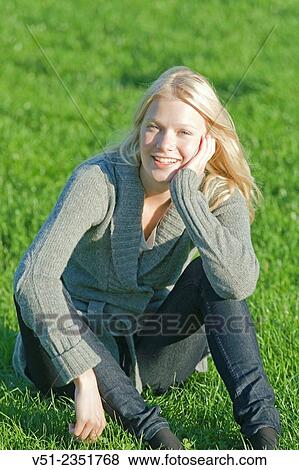 Portrait of a young woman sitting in the park and smiling at camera View Large Photo Image Stock Photo - Portrait of a young woman sitting in the park and smiling at camera. Fotosearch