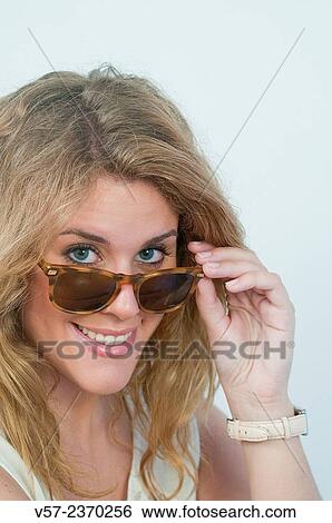 "Portrait of young woman wearing sunglasses, smiling and looking at the camera. Close view. " View Large Photo Image Stock Photograph - "Portrait of young woman wearing sunglasses, smiling and looking at the camera. Close view. ". Fotosearch