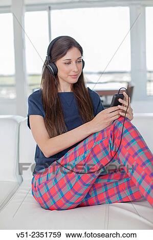 Pretty brunette woman listening to music on the sofa View Large Photo Image Stock Photo - Pretty brunette woman listening to music on the sofa. Fotosearch