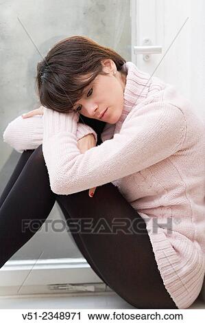 Stock Image - Sad Woman sitting at the windwow. Fotosearch