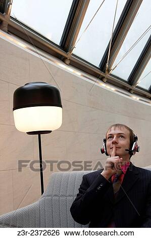Stock Photograph - Shh! Customer Relationship Management. Call center employee / manager talks over headset keeping trade secret. Freelancer working distantly with confidence.. Fotosearch