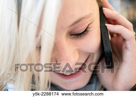 "Tilburg, Netherlands. Close up portrait of a young, blonde woman talking to her boy friend using her smart phone. " View Large Photo Image Picture - "Tilburg, Netherlands. Close up portrait of a young, blonde woman talking to her boy friend using her smart phone. ". Fotosearch