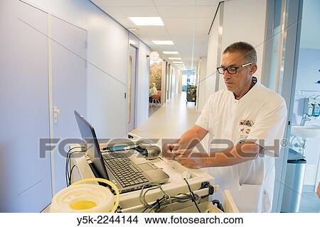 Picture - "Tilburg, Netherlands. Male nurse at an orthopedics nursing ward preparing medication for patients recovering surgery. ". Fotosearch