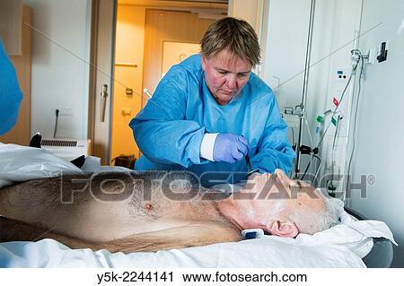 "Tilburg, Netherlands. Male orthopedic patient, recovering in a hospital sand bed to prevent decubitus, is nursed by a female nurse, wearing protective clothing against bacterial infection. " View Large Photo Image Stock Image - "Tilburg, Netherlands. Male orthopedic patient, recovering in a hospital sand bed to prevent decubitus, is nursed by a female nurse, wearing protective clothing against bacterial infection. ". Fotosearch